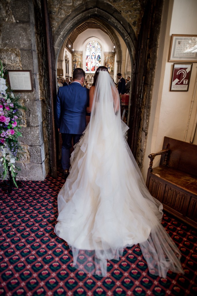 Father brings his daughter down the aisle, bride wear white wedding bridal dress with a very long lace veil and bridal crown in St marys church Maidstone Kent